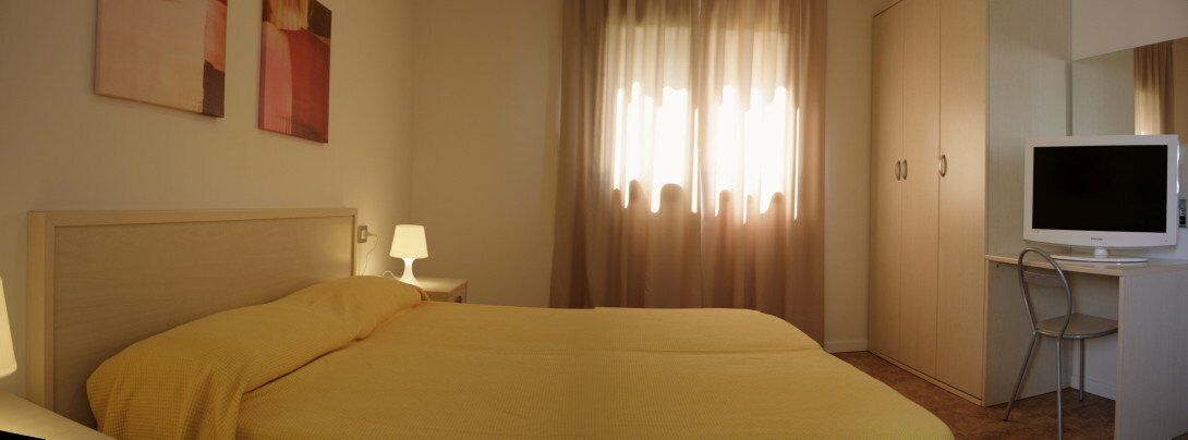 A hotel room with a bed, a television, a desk, and a chair.