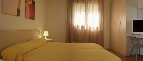 A hotel room with a bed, a television, a desk, and a chair.