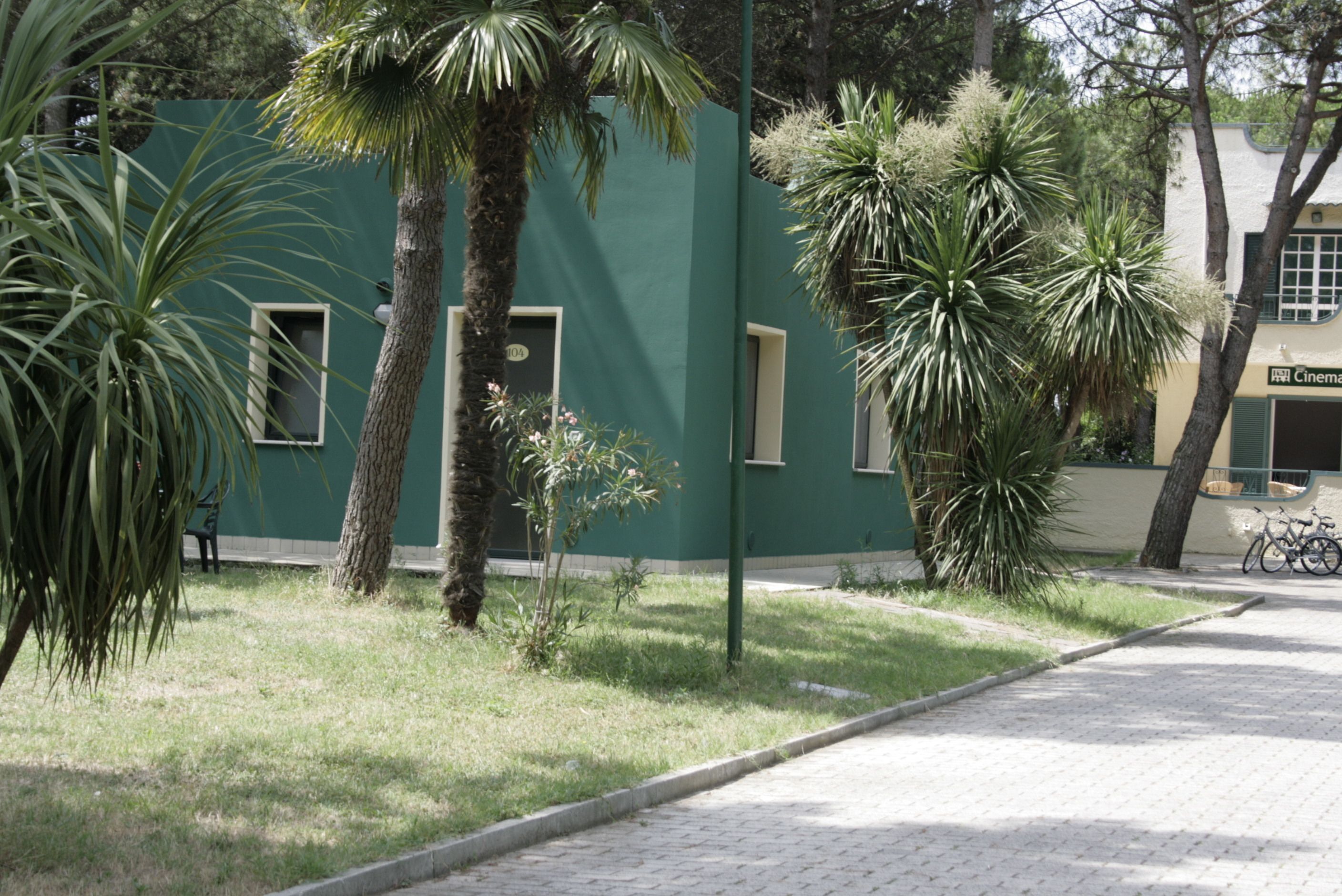 A building with a green facade, a paved sidewalk, and a bicycle parked nearby.