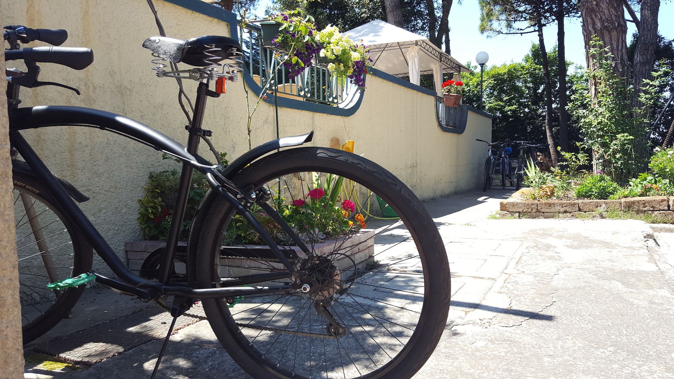 A bicycle parked in front of a building with a balcony and flower pots.