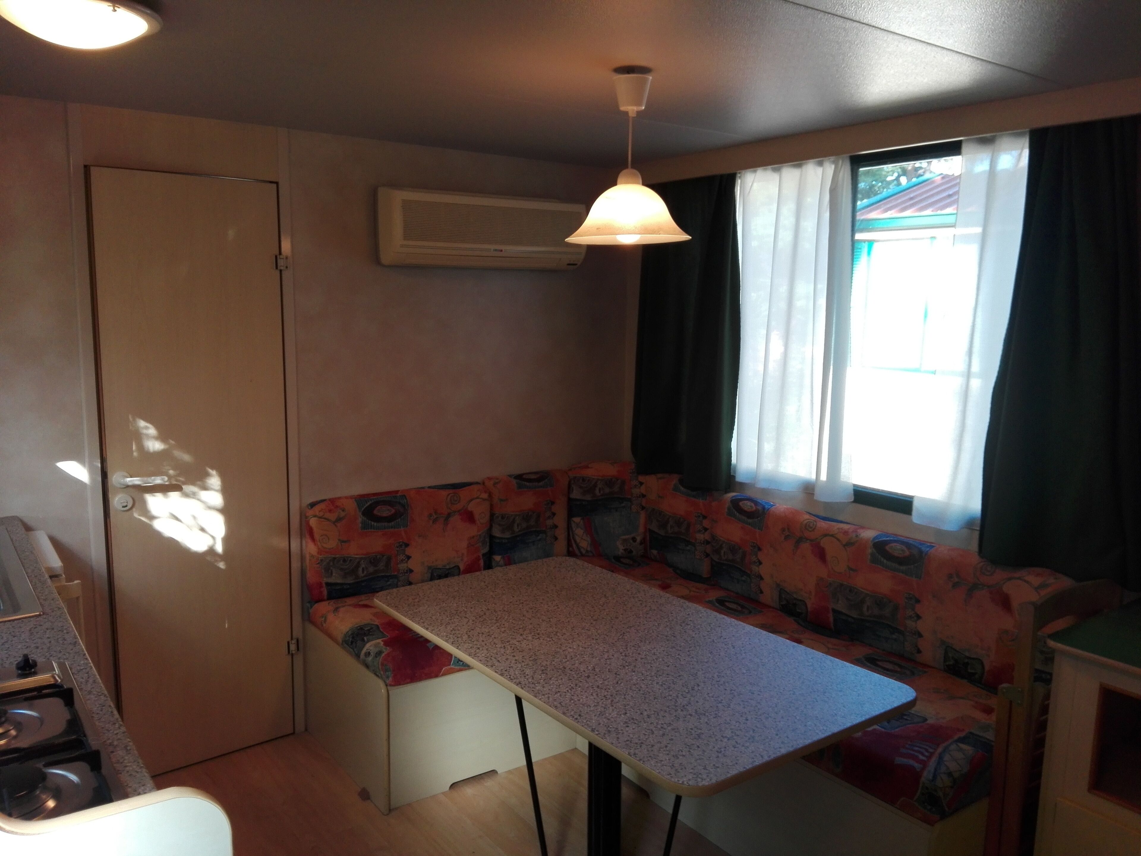 Une cuisine compacte équipée d’une cuisinière, d’un petit réfrigérateur et d’une table à manger avec un banc.