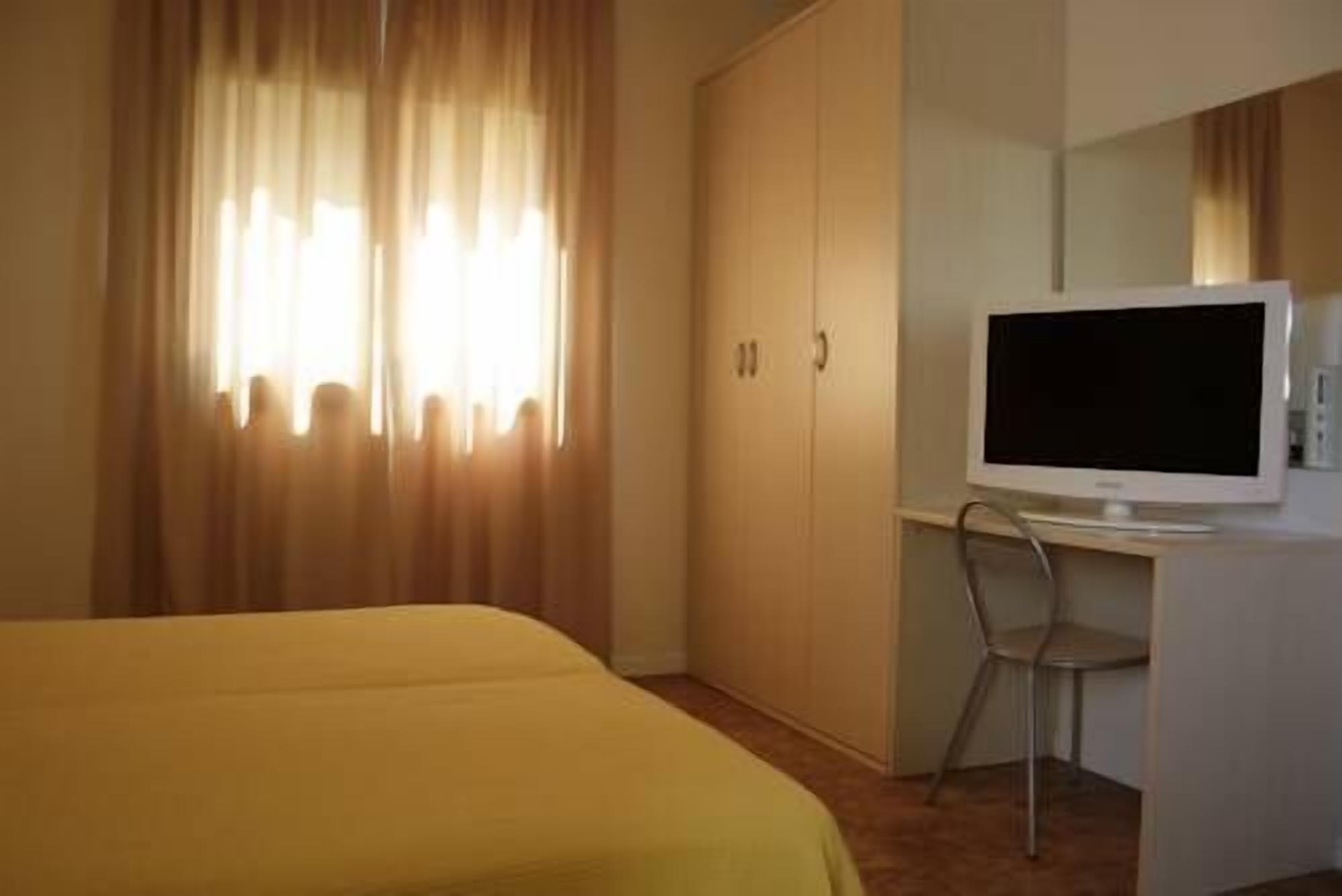 Ein Hotelzimmer mit einem Bett, einem Schreibtisch mit Fernseher und einem Sessel.