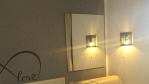 Una habitació d'hotel amb un llit, un sofà i dues làmpades fixes a la paret.