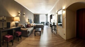 A modern hotel room with a sofa, two armchairs, a coffee table, a desk with a lamp, and a mirror. - Boutique Hotel Rango (Plzen)