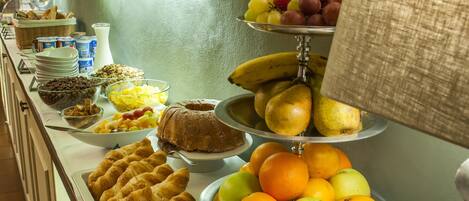 A buffet with various food items including fruits, pastries, and dairy products.