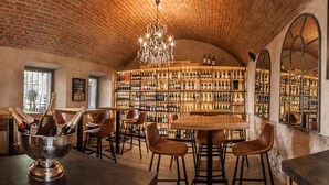 A cozy bar area with a brick ceiling, a chandelier, and a wine rack filled with bottles. - Boutique Hotel Rango (Plzen)