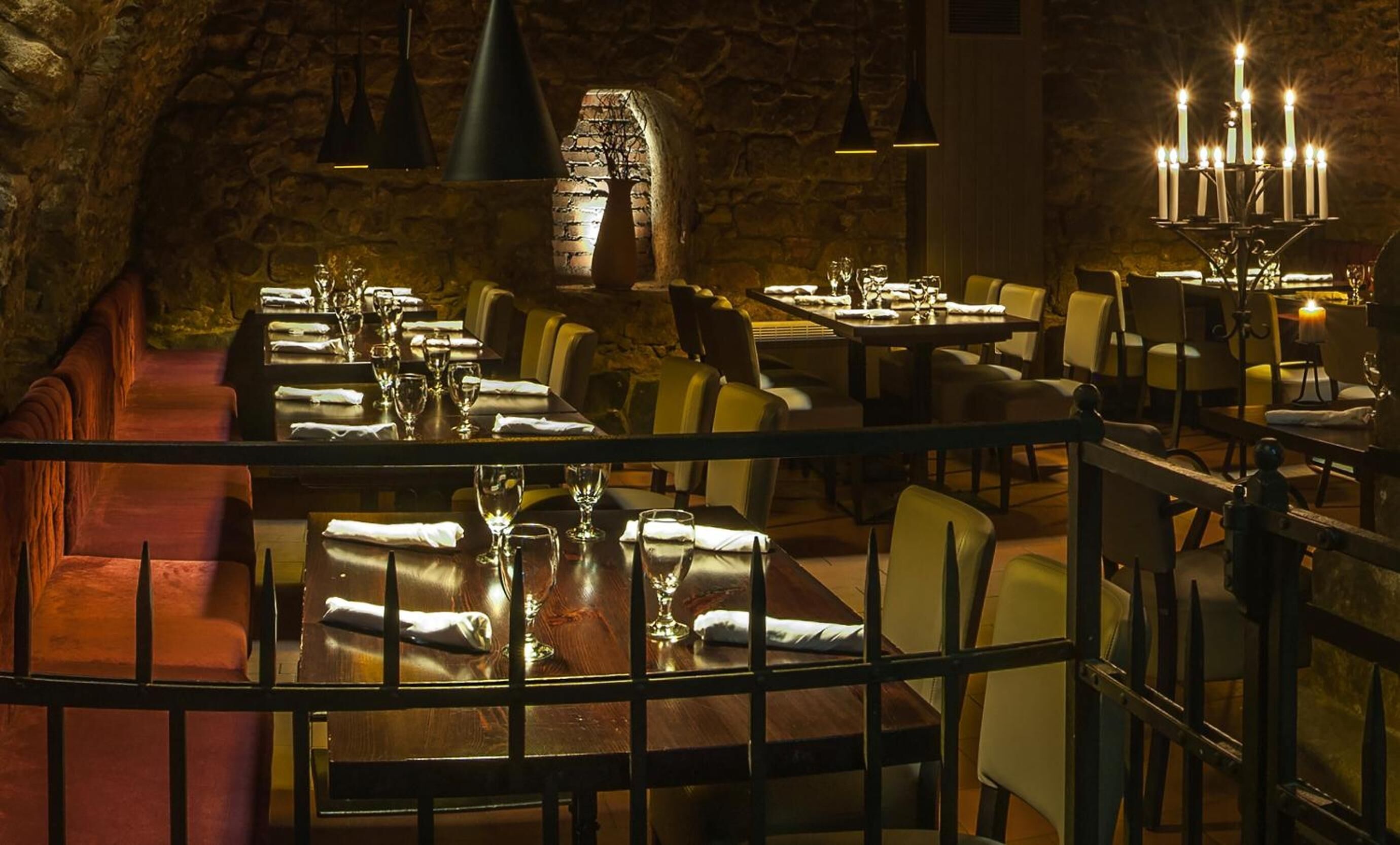 A dimly lit restaurant with stone walls and wooden tables set for dining.
