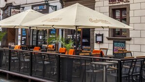 A hotel with outdoor seating, a sign for 'Hotel Restaurant Tango', and a 'MisterOptic.cz' sign.
