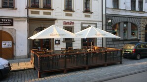 A restaurant with outdoor seating, a sign for 'Fango restaurant hotel', and a 'Budweiser' branded umbrella.