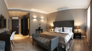 A modern hotel room with a large bed, a desk, a chair, and a sofa. - Boutique Hotel Rango (Plzen)