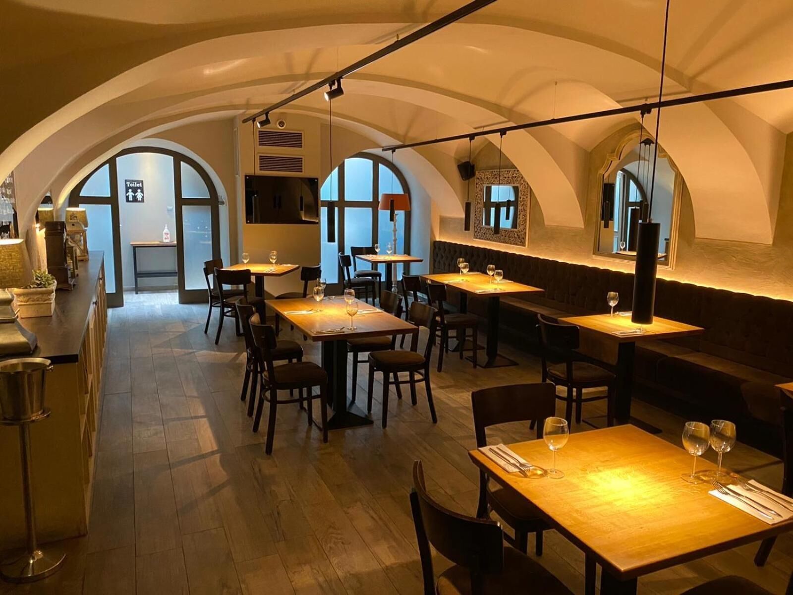Restaurante com interior acolhedor, com tetos em arco e mesas de madeira.