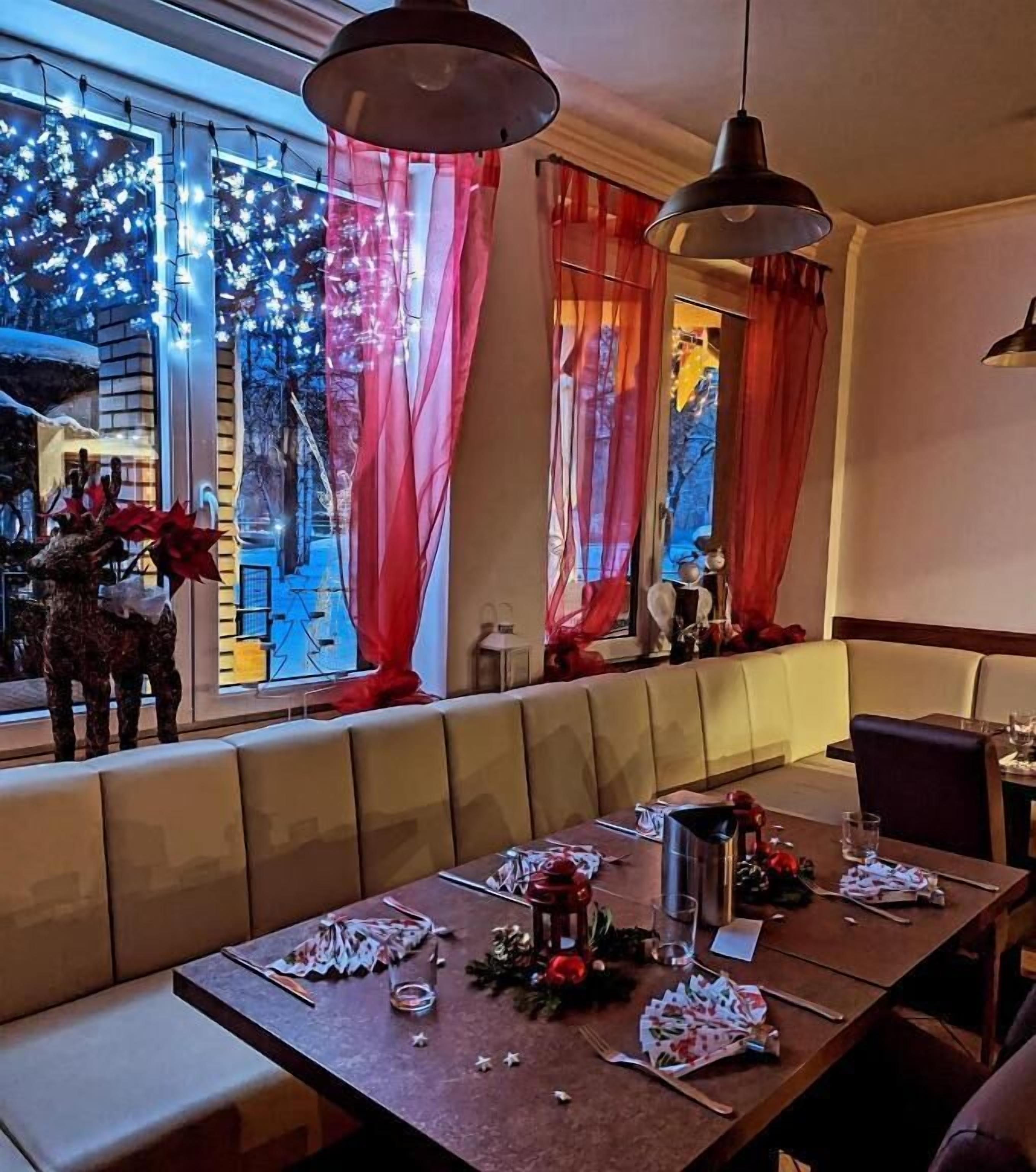A dining area with a booth seating arrangement, a table set for two, and a view of the street outside.