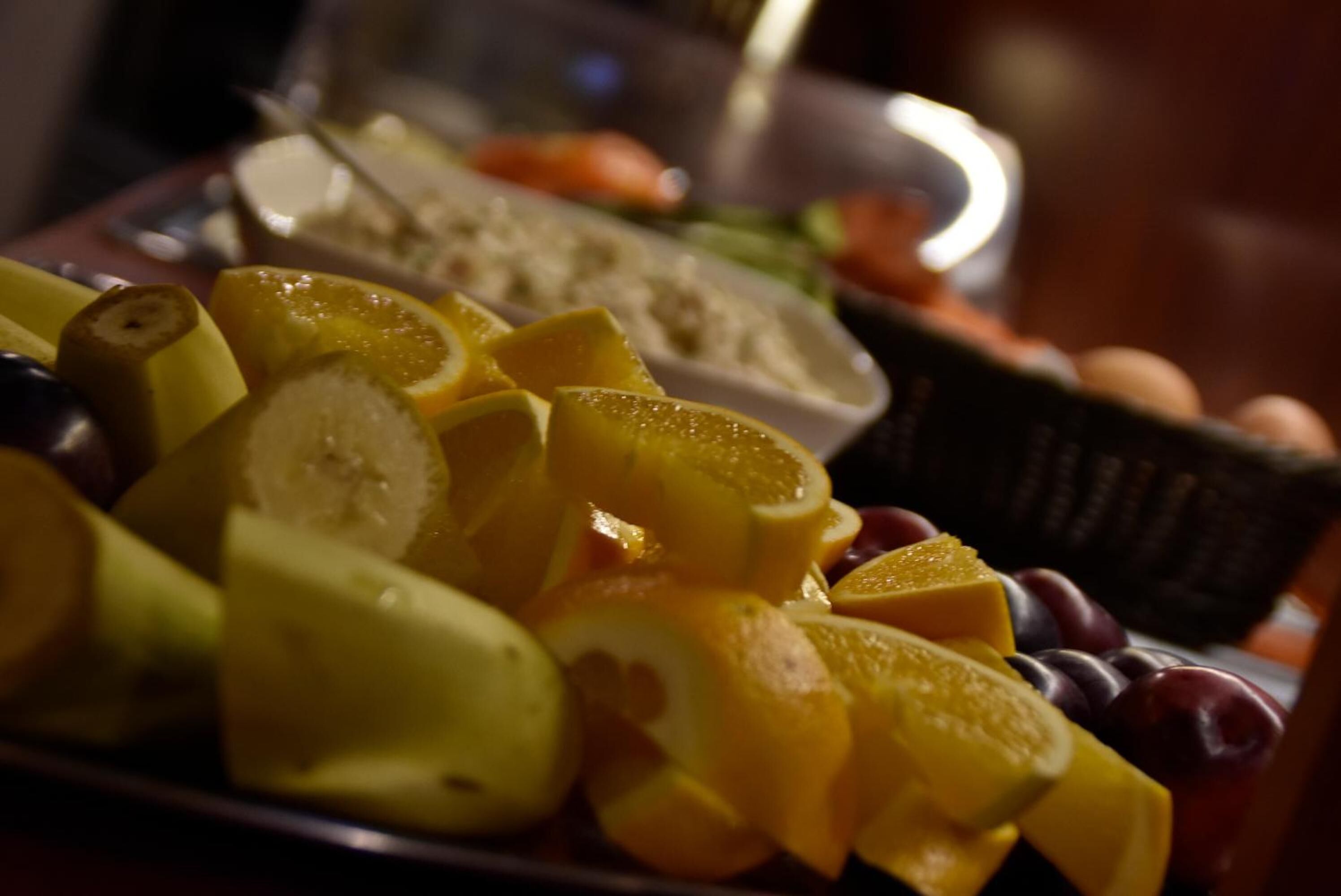 Un plato con rodajas de frutas, incluyendo plátanos, naranjas y uvas.