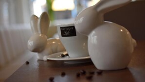Una mesa con tazas y platillos de cerámica con forma de conejo, una de ellas con la etiqueta 'DAVIDOFF Cafe'.