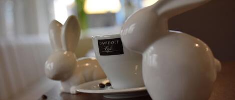 A table with ceramic rabbit-shaped coffee cups and saucers, one labeled "DAVIDOFF Cafe."