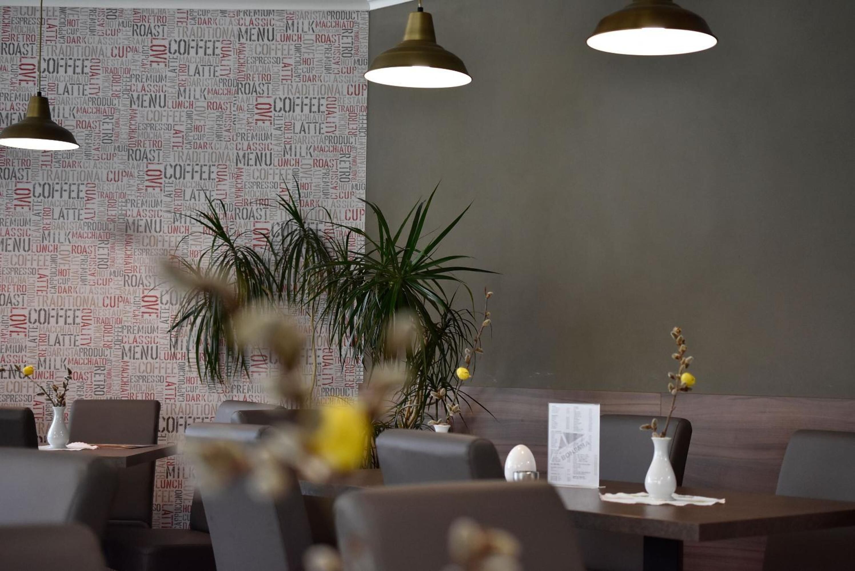 Ein Restaurantinneres mit einer Wand aus Wortwolken, moderner Pendelleuchten und einem Essbereich mit Tischen und Stühlen.