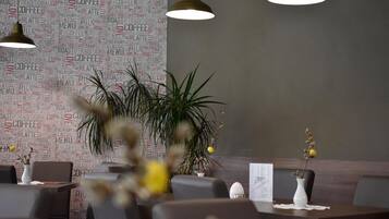 Ein Restaurantinneres mit einer Wand aus Wortwolken, moderner Pendelleuchten und einem Essbereich mit Tischen und Stühlen.