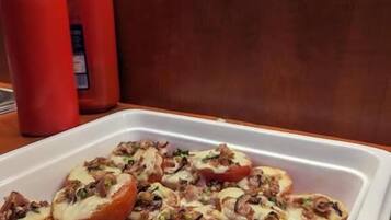 Una bandeja con tomates rellenos de queso y carne, sobre una mesa.