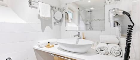 Uma casa de banho moderna com lavatório branco, espelho e barra de toalhas.