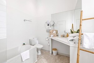 Een moderne badkamer met een bad, toilet en wastafel.
