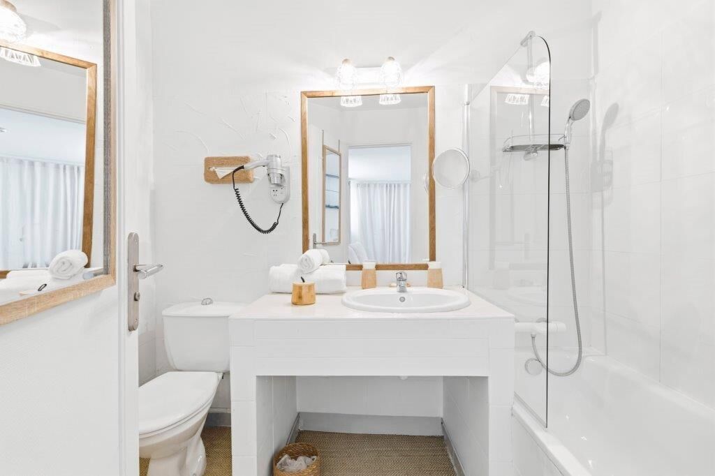 A modern bathroom with a white sink, mirror, and shower.
