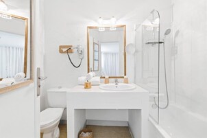 Ein modernes Badezimmer mit einem weißen Waschbecken, Spiegel und Dusche.