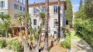 A large building with multiple windows, a wooden deck, and surrounding greenery. - Villa Claudia Hotel Cannes Centre - Parking (Cannes)