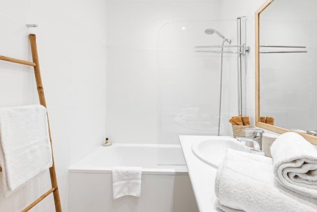 A bathroom with a bathtub, shower, and sink, all in white.