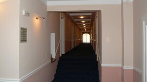 Ein Hotel-Flur mit Teppichstufen, hellen Wänden und einer Tür am Ende.