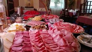 Ein Buffet mit verschiedenen Speisen, darunter Fleisch, Käse und Obst.