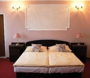A neatly made bed with two pillows, a black headboard, and two bedside tables with lamps. - Eurohotel Garni (Karlovy Vary)