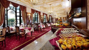 A formal dining area with tables set for service, a buffet with various food items, and a view of the outside through large windows. - Hotel Excelsior (Marianske Lazne)