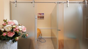 A room with a sliding door, a white vase with flowers, and a painting on the wall. - Hotel Excelsior (Marianske Lazne)
