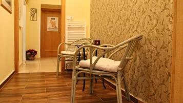 A hallway with wicker chairs, a radiator, and a door with a poster.