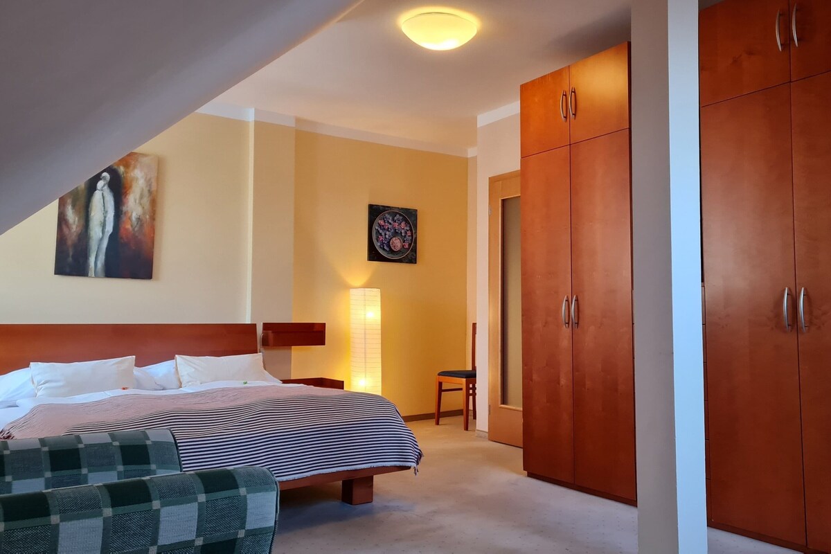 Habitación de hotel con cama, una silla, armario y un cuadro en la pared.