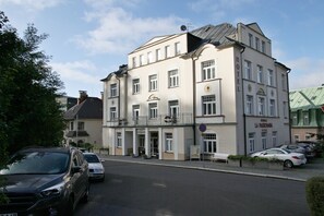 Un hotel de estilo arquitectónico europeo clásico, con fachada simétrica, varias ventanas y un balcón en el segundo piso.