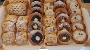 Una bandeja con diversos pasteles, incluyendo rosquillas rellenas y enrolladas, algunas espolvoreadas con azúcar glas.