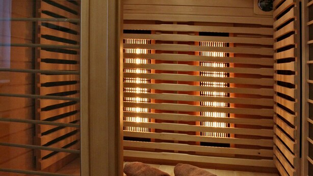 Una sauna con listones de madera, un banco y un calentador pequeño.