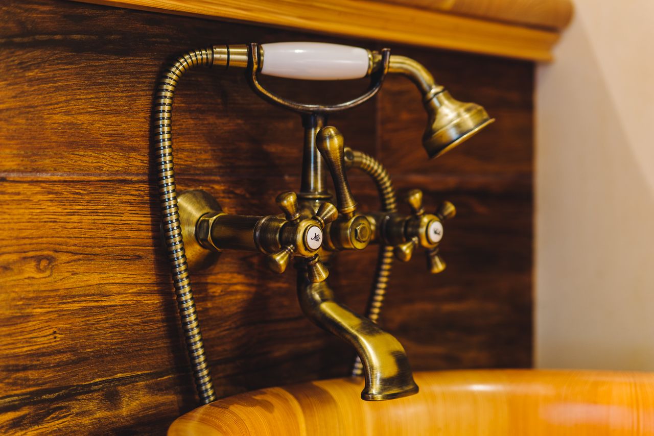 Un accesorio de baño de bronce con un mando blanco y una manguera flexible.