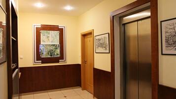 A hallway with a wooden door, a framed map, and an elevator.