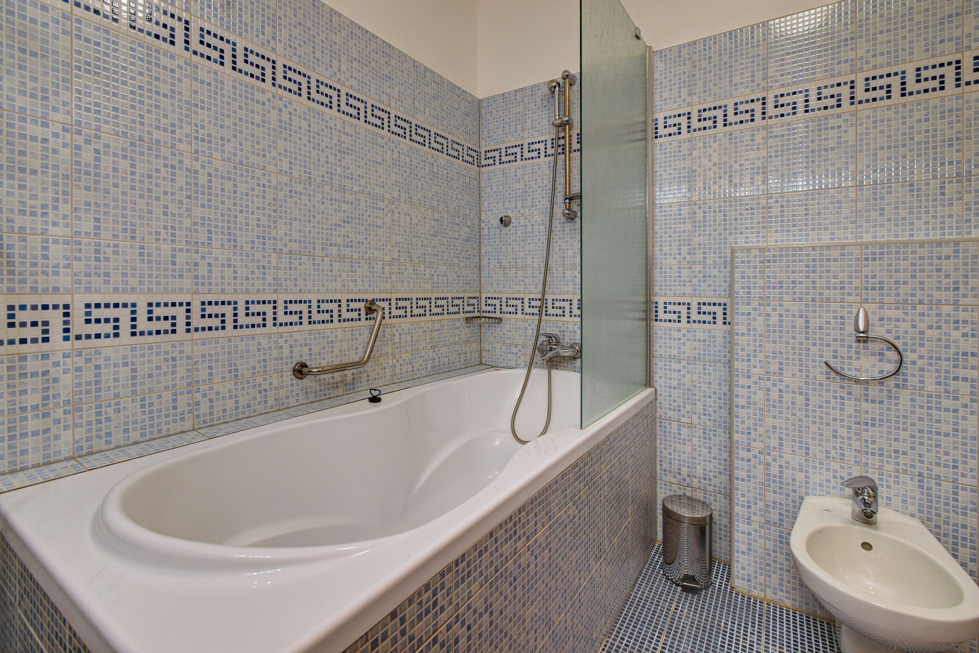 A bathroom with a white bathtub, a glass-enclosed shower, and a white sink.