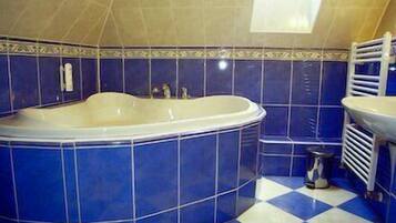 Ein Badezimmer mit einer großen Badewanne, einem blau-weißen Schachfußboden und einem Oberlicht über der Wanne.