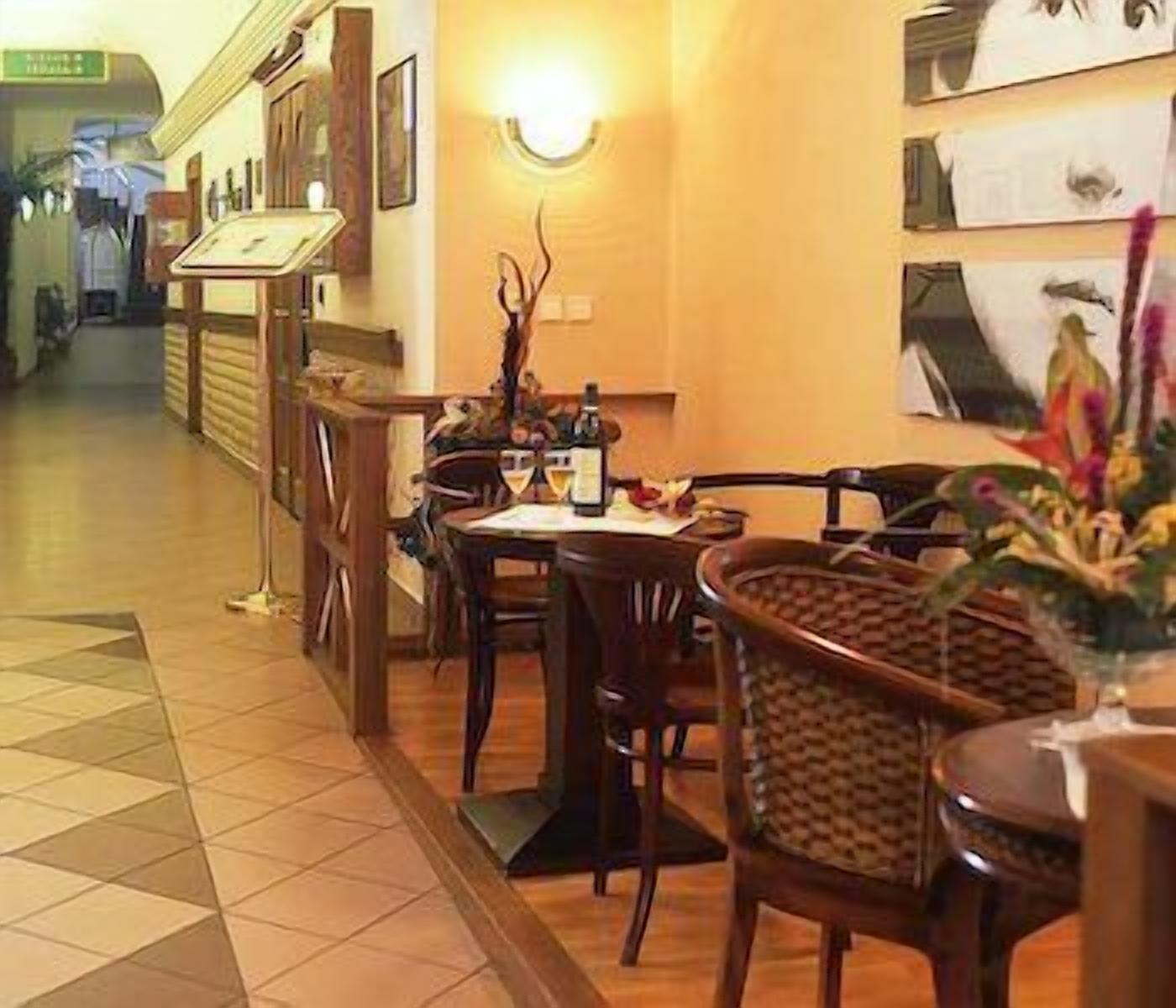 L’intérieur d’un restaurant est aménagé avec des meubles en bois, un sol carrelé et un luminaire fixé au mur.