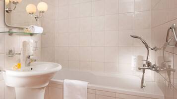 A modern bathroom with a white sink, glass shelf, and a bathtub with a showerhead.