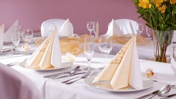 Une table dressée pour un repas formel, avec des nappes blanches, des serviettes pliées et de la verrerie transparente.