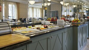 A buffet setup with various food items, a wooden cutting board, and a mirror reflecting the room.