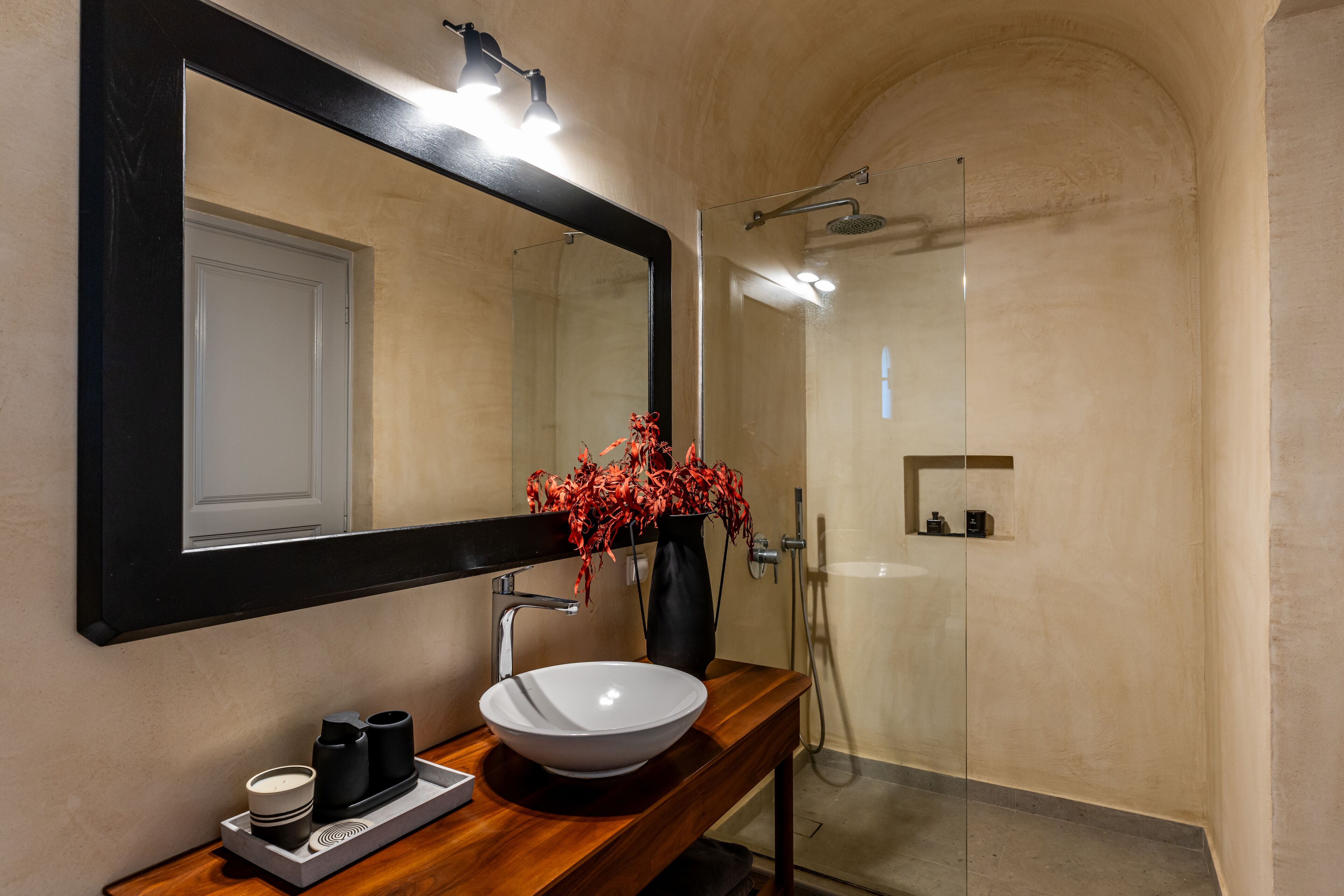 A modern bathroom with a large mirror, a white sink, and a shower.