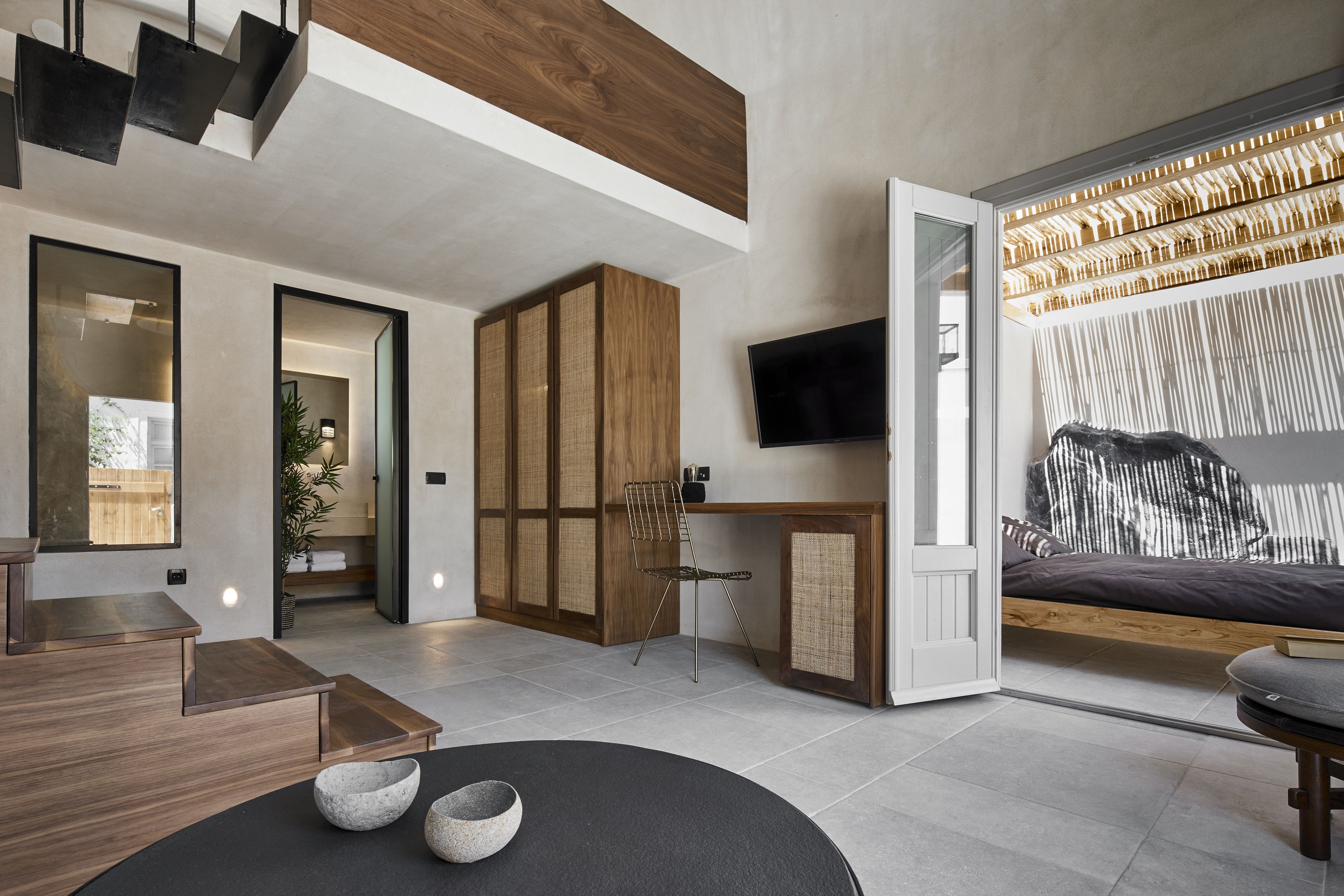 A modern living room with a wooden cabinet, a black sofa, and a dining table.