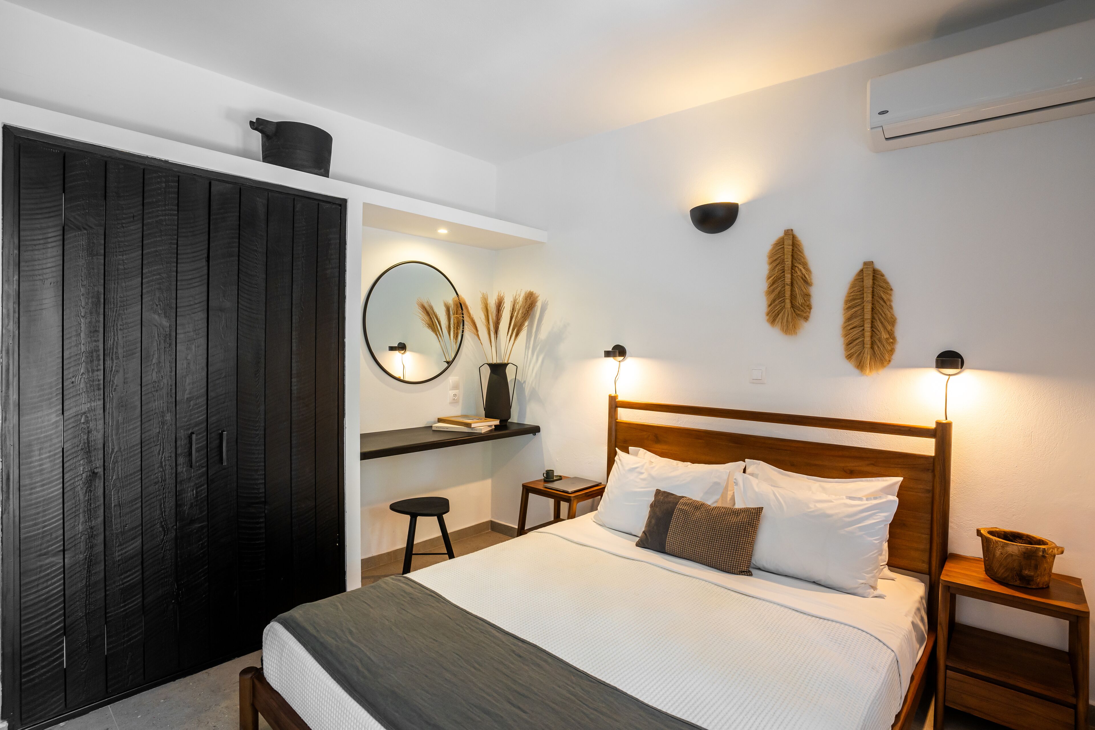 A bedroom with a bed, bedside tables, a wardrobe, a mirror, and wall-mounted lights.