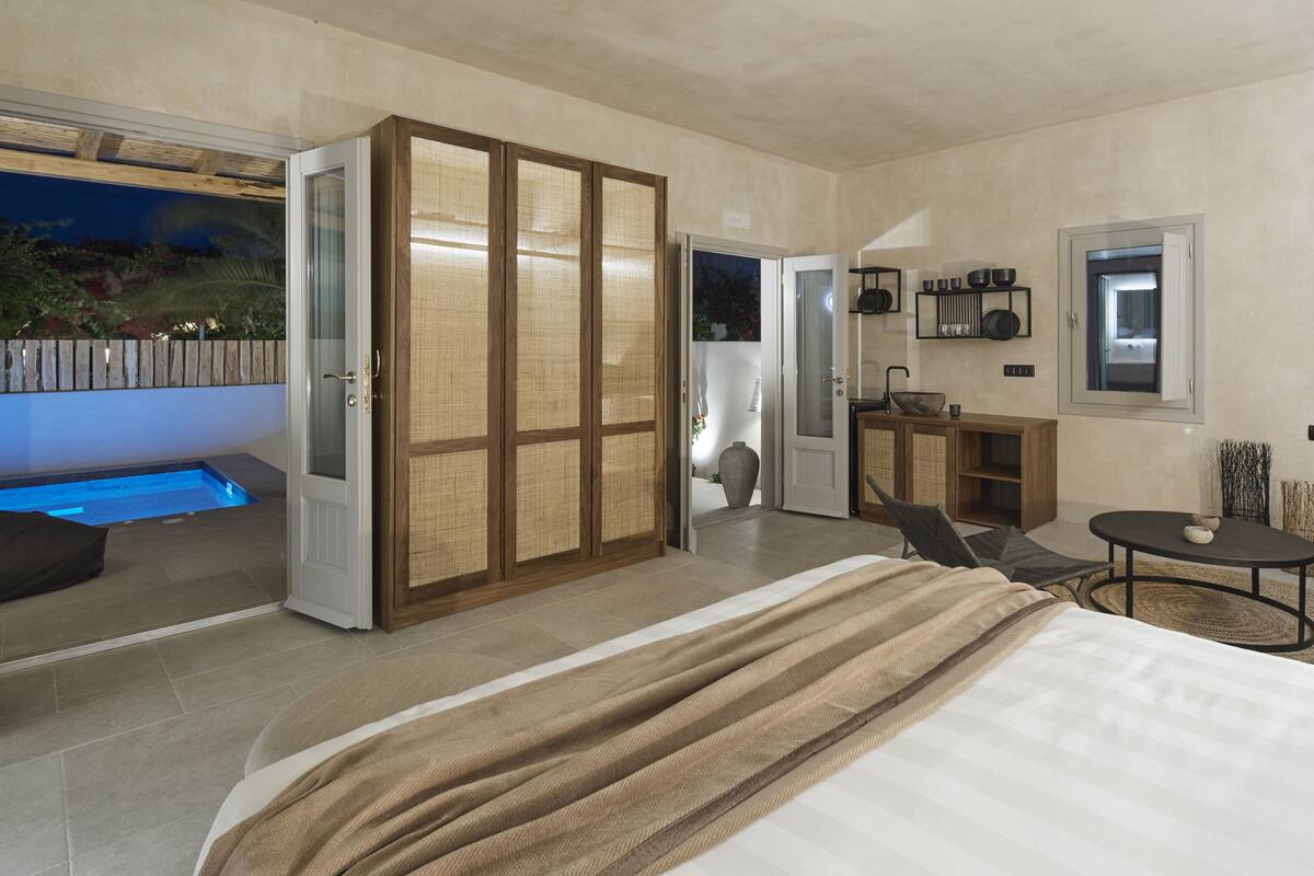 A modern bedroom with a large bed, a small table, and a built-in bench.